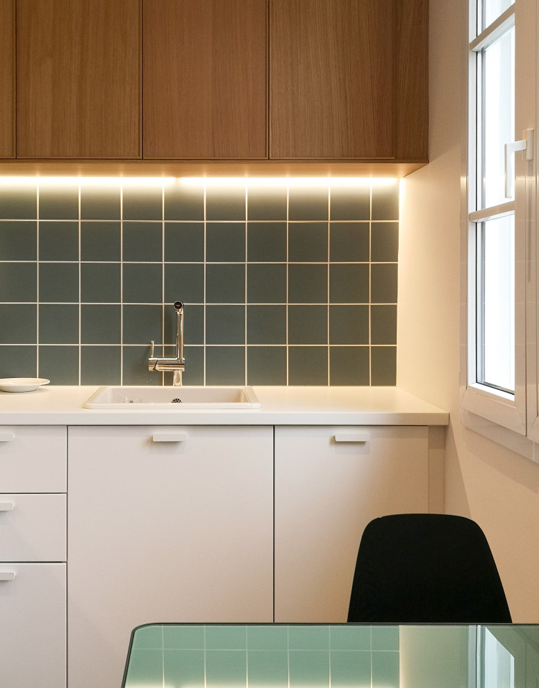 Photo of a large contemporary l-shaped separate kitchen in Reims with an undermount sink, beaded inset cabinets, white cabinets, laminate benchtops, green splashback, ceramic splashback, panelled appliances, linoleum floors, multi-coloured floor and white benchtop.