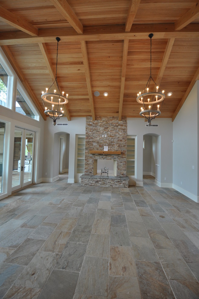 Large arts and crafts living room in New Orleans with slate floors, a standard fireplace and a stone fireplace surround.