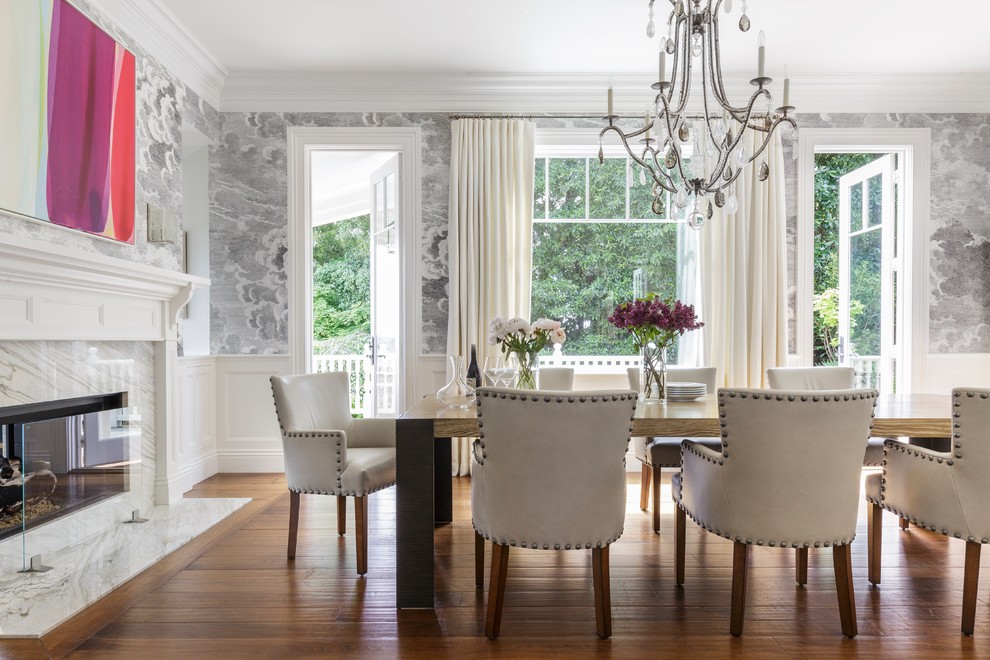 Inspiration for a transitional dining room in San Francisco with grey walls, medium hardwood floors, a two-sided fireplace, a stone fireplace surround and brown floor.