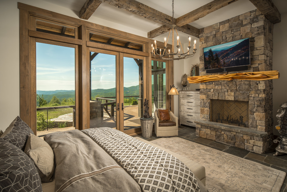 Design ideas for a mid-sized country guest bedroom in Charlotte with beige walls, slate floors, grey floor, a standard fireplace and a stone fireplace surround.
