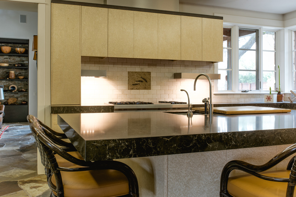 This is an example of a large midcentury u-shaped eat-in kitchen in Dallas with an undermount sink, flat-panel cabinets, light wood cabinets, quartz benchtops, beige splashback, limestone splashback, stainless steel appliances, slate floors and with island.