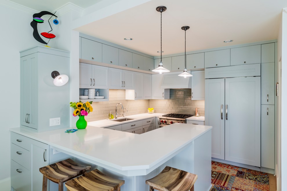 Design ideas for a small beach style u-shaped kitchen in Portland with an undermount sink, shaker cabinets, blue cabinets, grey splashback, subway tile splashback, panelled appliances, a peninsula, white benchtop, quartz benchtops, light hardwood floors and beige floor.