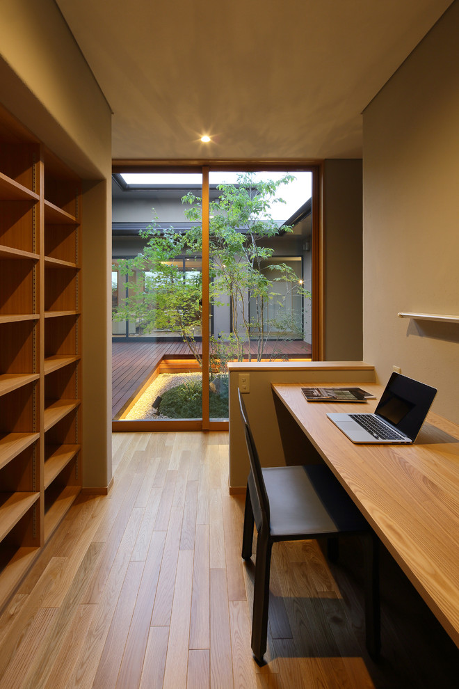 This is an example of an asian home office in Other with brown walls, medium hardwood floors, a built-in desk and brown floor.