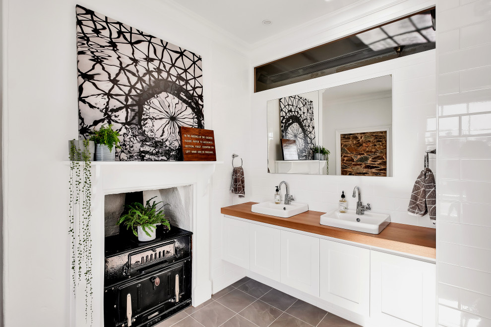 Inspiration for a large contemporary master bathroom in Adelaide with shaker cabinets, white cabinets, white tile, porcelain floors, a drop-in sink, wood benchtops, grey floor, a floating vanity, subway tile, white walls, brown benchtops and a double vanity.