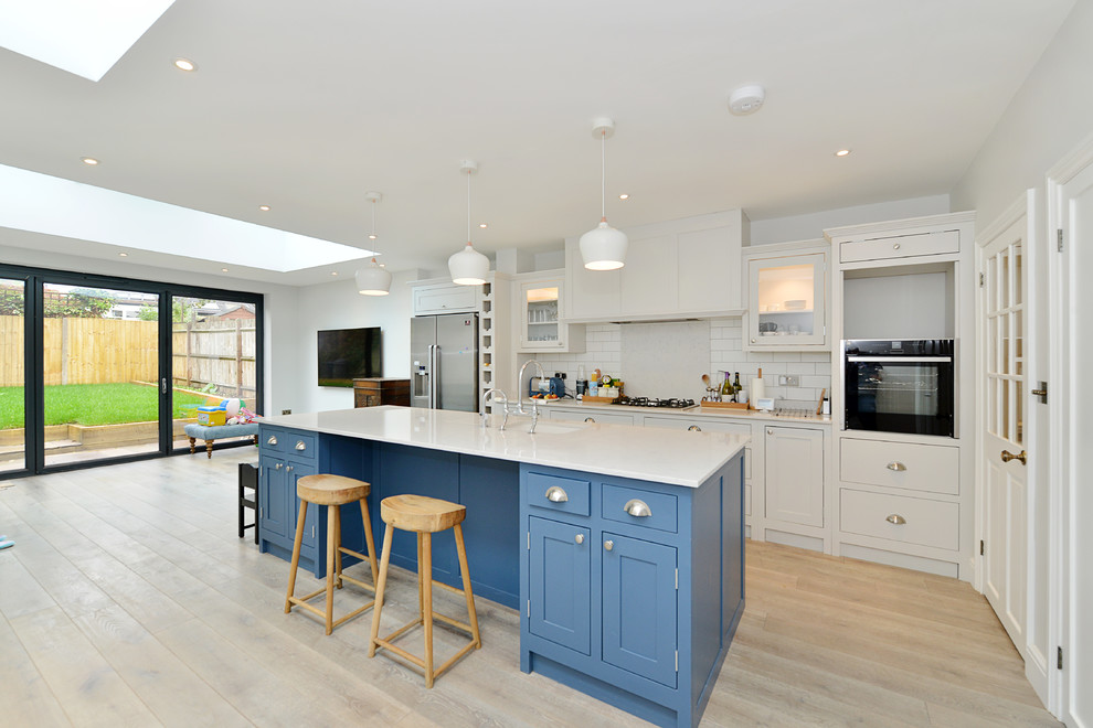 Inspiration for a mid-sized transitional u-shaped eat-in kitchen in London with a drop-in sink, flat-panel cabinets, white cabinets, wood benchtops, blue splashback, brick splashback, coloured appliances, dark hardwood floors, with island and brown floor.