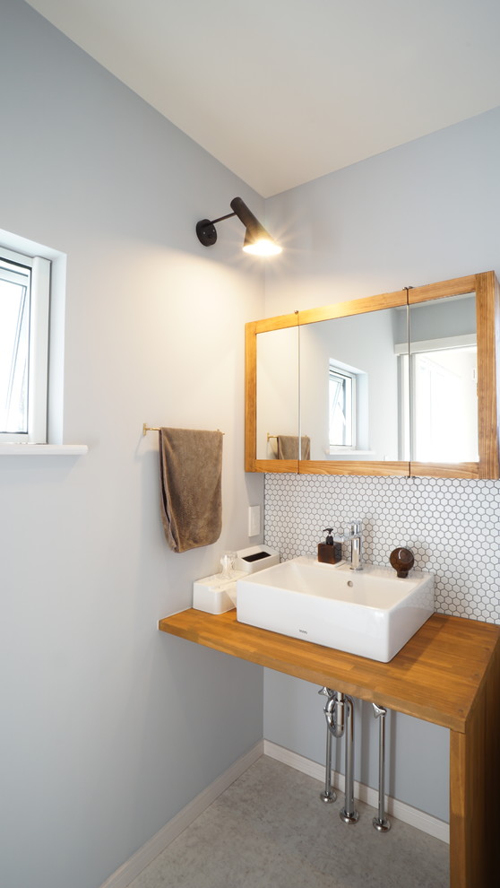 Small scandinavian powder room in Other with open cabinets, white tile, blue walls, a vessel sink and grey floor.