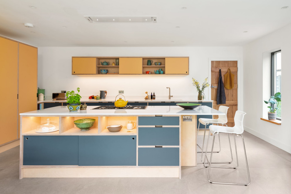 Inspiration for a mid-sized contemporary kitchen in Oxfordshire with an undermount sink, flat-panel cabinets, yellow cabinets, concrete floors, with island, grey floor and white benchtop.