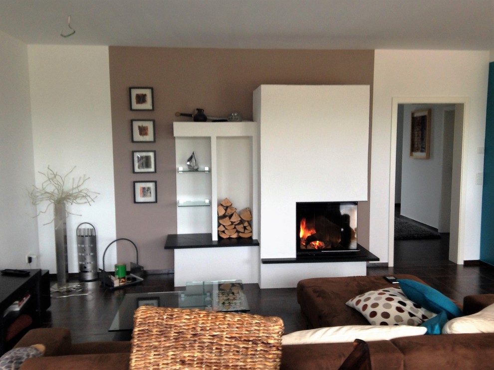 Mittelgroßes, Repräsentatives, Offenes Modernes Wohnzimmer mit weißer Wandfarbe, Eckkamin, verputzter Kaminumrandung und schwarzem Boden in Köln