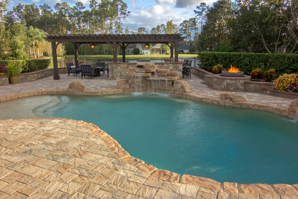 Design ideas for a large traditional backyard pool in Jacksonville with natural stone pavers.