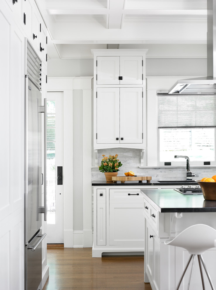 Kitchen - transitional medium tone wood floor kitchen idea in Atlanta with an undermount sink, white cabinets, soapstone countertops, white backsplash, stone tile backsplash, stainless steel appliances, shaker cabinets and an island