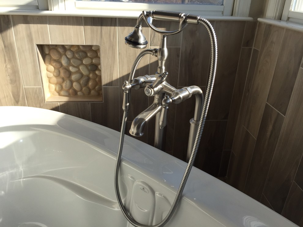 Freestanding bathtub - large transitional master gray tile and porcelain tile light wood floor and brown floor freestanding bathtub idea in Baltimore with shaker cabinets, dark wood cabinets, a two-piece toilet, beige walls, an undermount sink, solid surface countertops and a hinged shower door