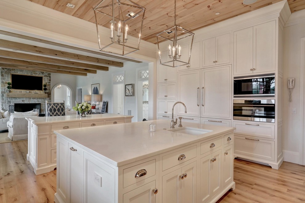 Design ideas for a large country galley open plan kitchen in Baltimore with a farmhouse sink, white cabinets, white splashback, stainless steel appliances, medium hardwood floors, multiple islands and brown floor.