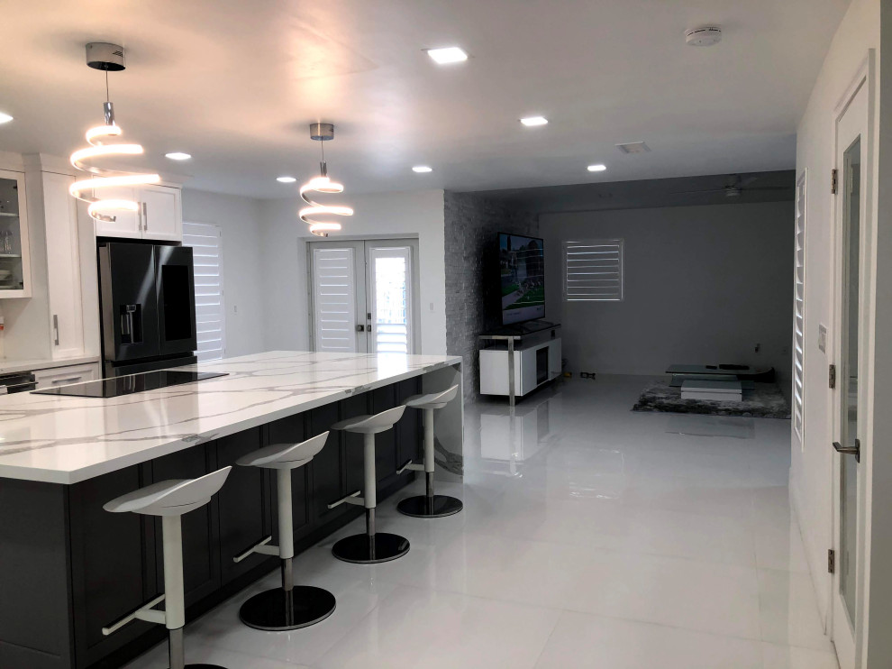 Eat-in kitchen - transitional single-wall porcelain tile and white floor eat-in kitchen idea in Miami with an undermount sink, shaker cabinets, white cabinets, quartz countertops, white backsplash, mosaic tile backsplash, stainless steel appliances and an island