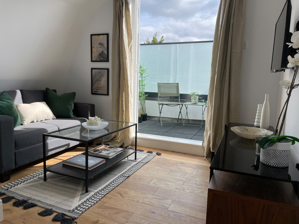 Esempio di un piccolo soggiorno contemporaneo aperto con pareti bianche, pavimento in legno massello medio, TV a parete e pavimento marrone