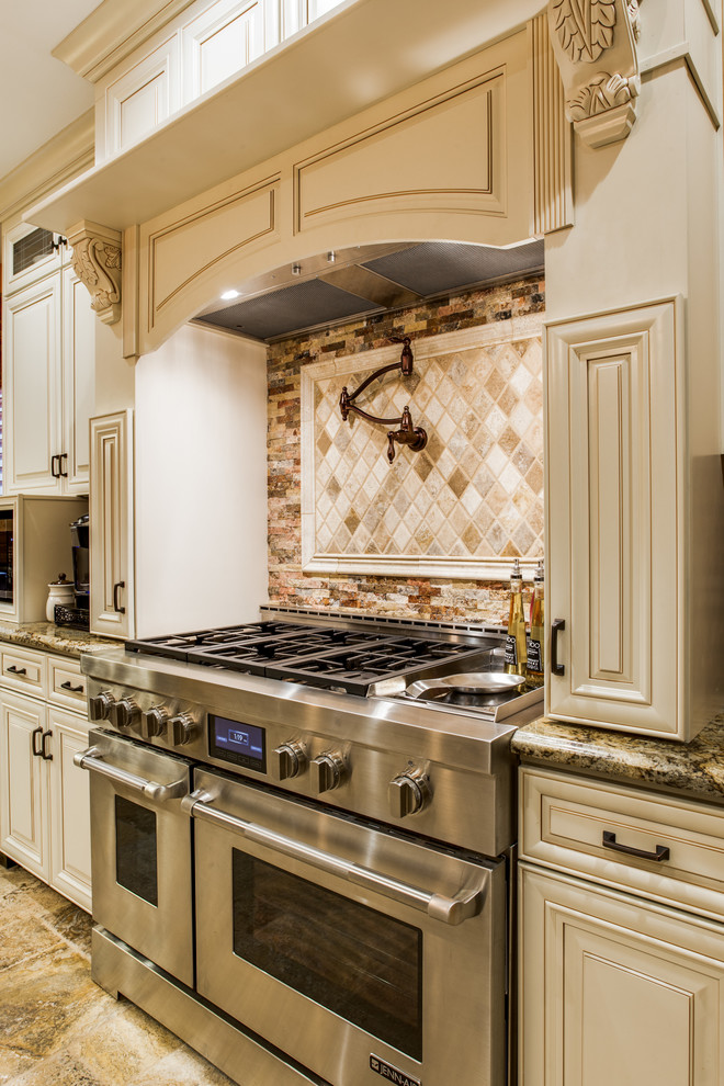 Inspiration for a large traditional galley separate kitchen in Dallas with a farmhouse sink, raised-panel cabinets, white cabinets, granite benchtops, multi-coloured splashback, mosaic tile splashback, stainless steel appliances, terra-cotta floors and with island.