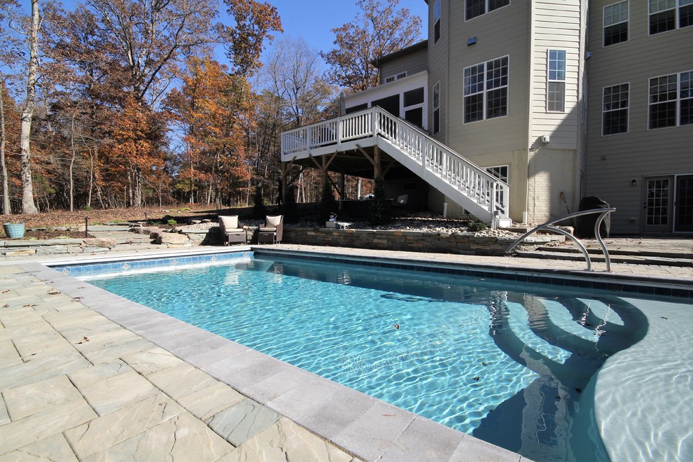 Example of a large mountain style backyard concrete paver and rectangular pool design in DC Metro