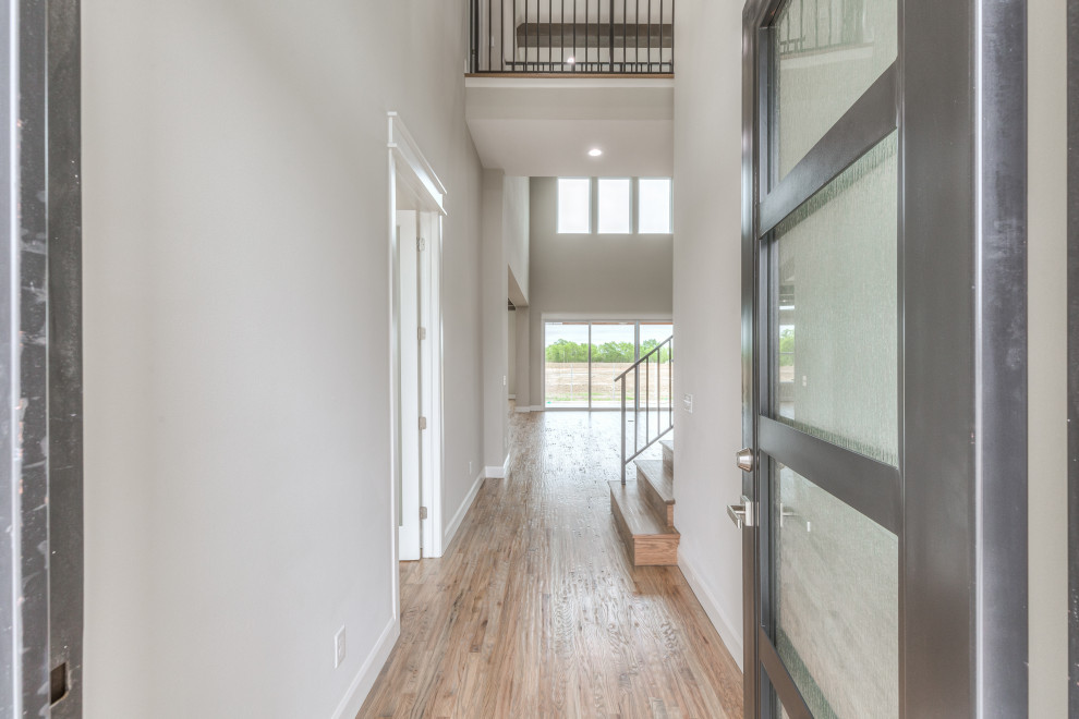 Front door - transitional light wood floor and vaulted ceiling front door idea with gray walls and a black front door