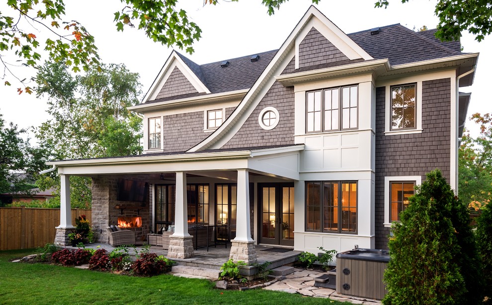 Large arts and crafts two-storey brown house exterior in Toronto with a hip roof, wood siding and a mixed roof.