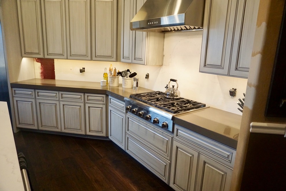 Mid-sized transitional l-shaped dark wood floor and brown floor enclosed kitchen photo in Phoenix with an undermount sink, raised-panel cabinets, white cabinets, quartz countertops, stainless steel appliances and an island