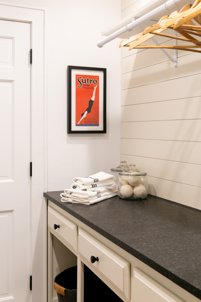 Design ideas for a mid-sized transitional galley dedicated laundry room in New York with an utility sink, shaker cabinets, white cabinets, granite benchtops, white splashback, shiplap splashback, white walls, porcelain floors, a side-by-side washer and dryer, beige floor, black benchtop and planked wall panelling.