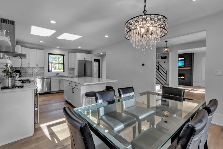 Inspiration for a mid-sized transitional l-shaped light wood floor and brown floor eat-in kitchen remodel with an undermount sink, shaker cabinets, white cabinets, quartz countertops, white backsplash, ceramic backsplash, stainless steel appliances, an island and white countertops