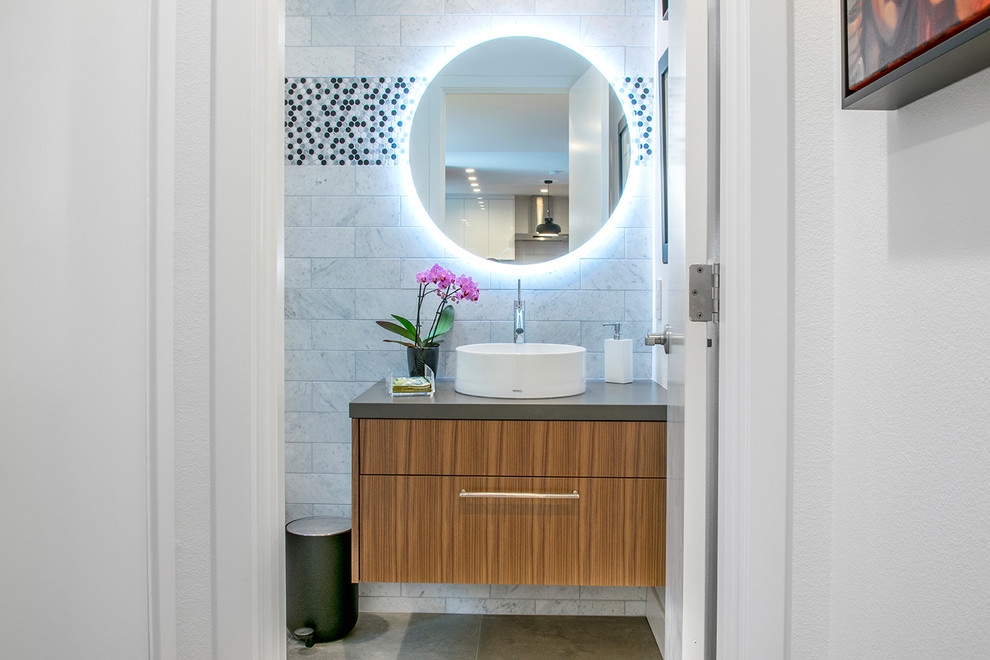 Photo of a contemporary powder room in Orange County with flat-panel cabinets, medium wood cabinets, gray tile, a vessel sink, beige floor and grey benchtops.