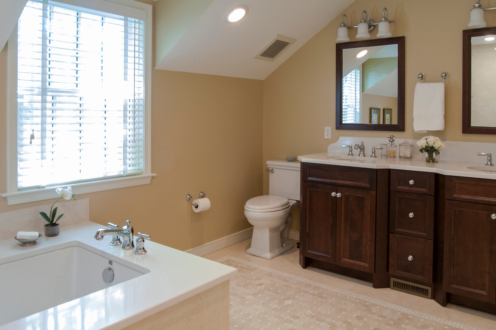 Mid-sized traditional master bathroom in Philadelphia with an undermount sink, recessed-panel cabinets, dark wood cabinets, marble benchtops, an undermount tub, a two-piece toilet, beige tile, stone tile, beige walls and marble floors.