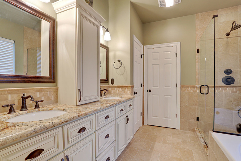 This is an example of a traditional bathroom in New Orleans with an undermount sink, raised-panel cabinets, white cabinets, granite benchtops, a drop-in tub, an open shower, beige tile and porcelain tile.