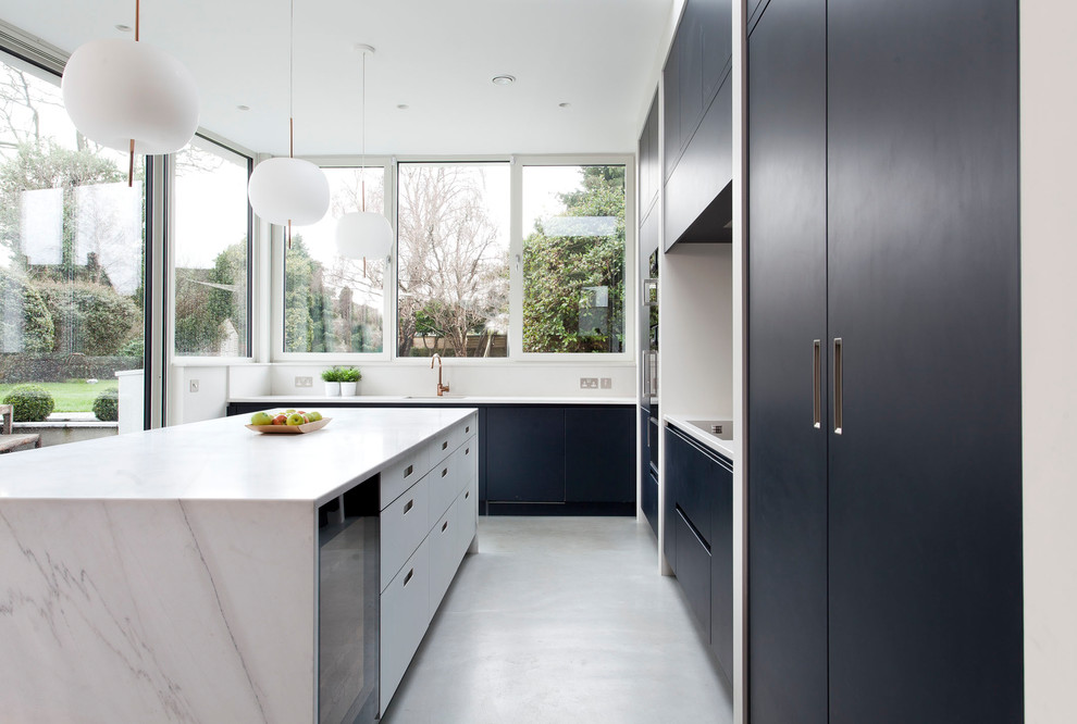 Inspiration for a modern l-shaped open plan kitchen in Other with a drop-in sink, flat-panel cabinets, blue cabinets, marble benchtops, white splashback, marble splashback, black appliances, concrete floors, with island, grey floor and white benchtop.