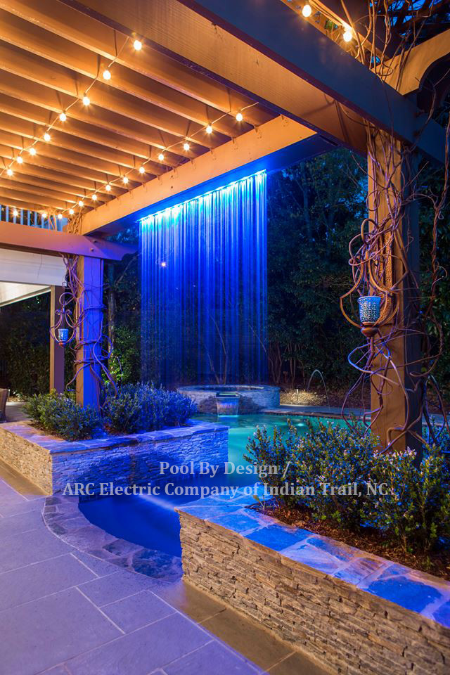 Example of a huge backyard tile and custom-shaped hot tub design in Charlotte