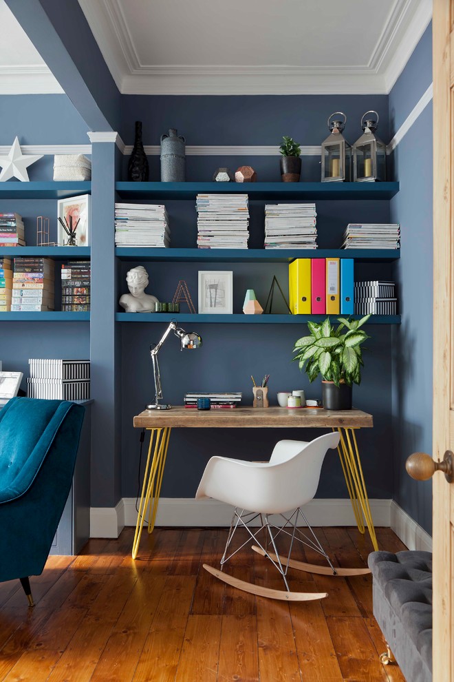 This is an example of a mid-sized transitional home office in London with blue walls, medium hardwood floors, a freestanding desk and brown floor.