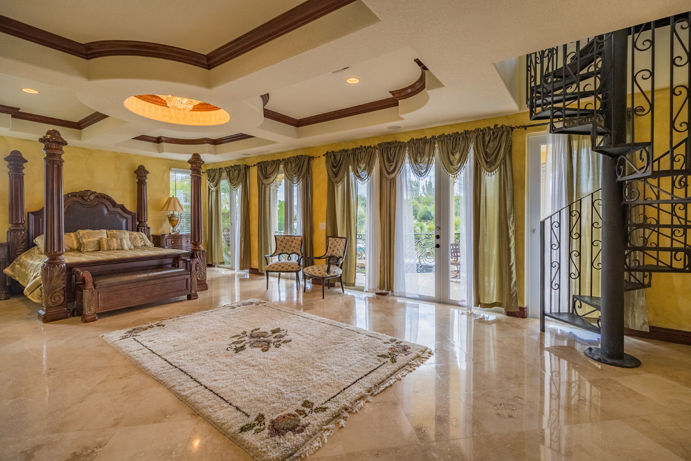 This is an example of an expansive mediterranean master bedroom in Miami with yellow walls, marble floors, no fireplace and beige floor.