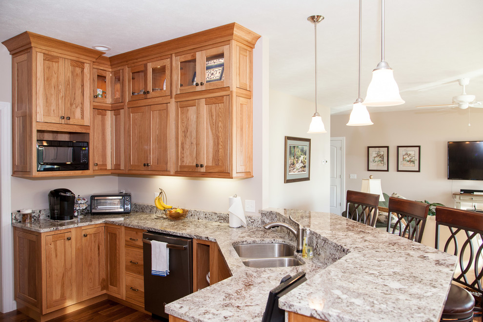 Example of a mid-sized mountain style u-shaped medium tone wood floor eat-in kitchen design with an undermount sink, shaker cabinets, light wood cabinets, granite countertops, stainless steel appliances and a peninsula
