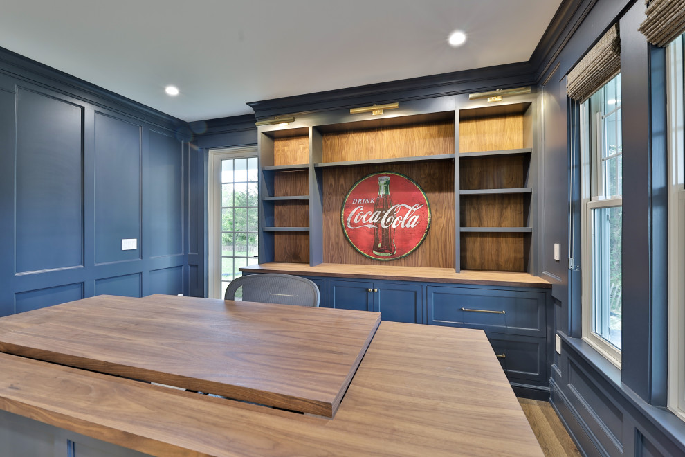 Großes Landhausstil Lesezimmer mit Einbau-Schreibtisch, blauer Wandfarbe, dunklem Holzboden, braunem Boden und vertäfelten Wänden in Philadelphia