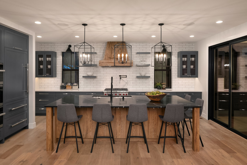 Inspiration for a large country open plan kitchen in Seattle with shaker cabinets, grey cabinets, white splashback, brick splashback, stainless steel appliances, medium hardwood floors, with island and white benchtop.