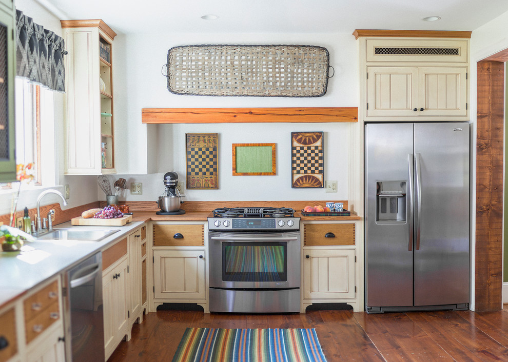 Inspiration for a mid-sized country l-shaped kitchen in Philadelphia with a drop-in sink, beaded inset cabinets, beige cabinets, stainless steel appliances, medium hardwood floors, no island and wood benchtops.