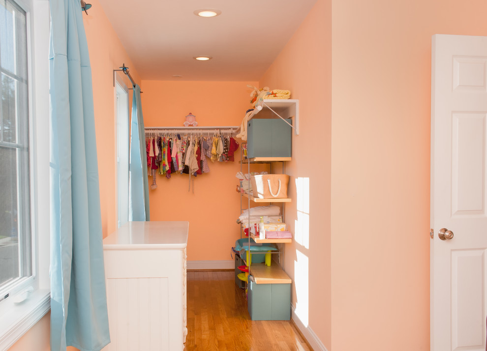 This is an example of a mid-sized traditional nursery for girls in DC Metro with medium hardwood floors, pink walls and brown floor.
