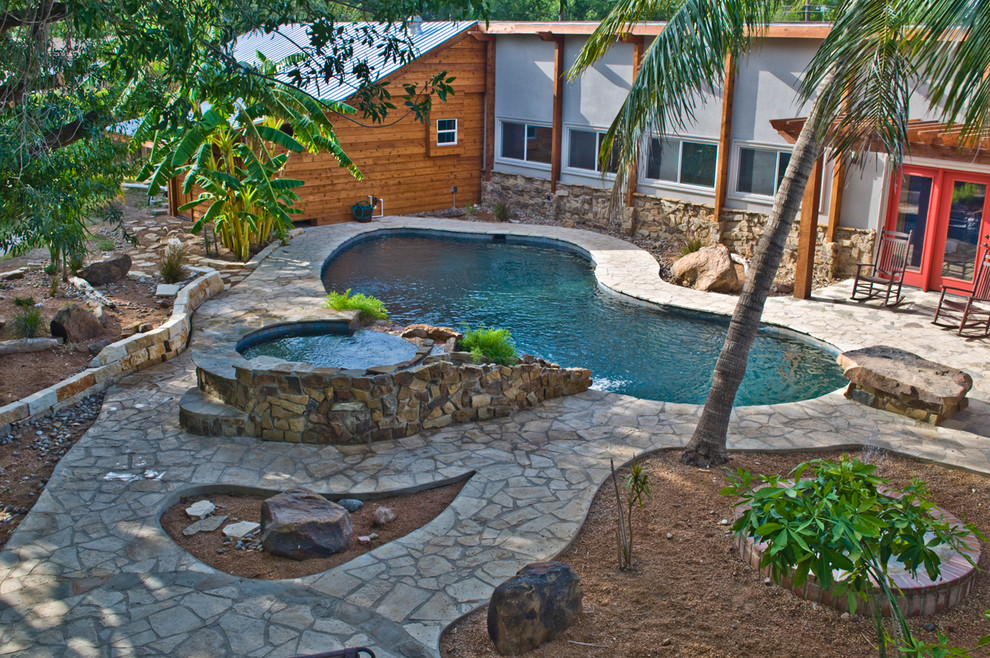 Example of a huge island style backyard custom-shaped pool design in Austin