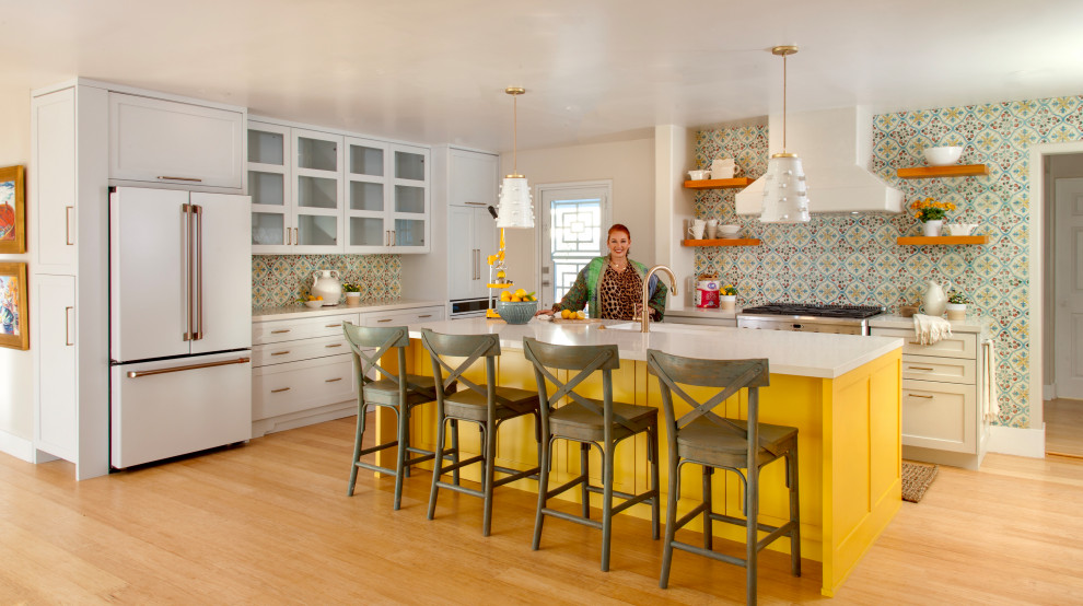 Inspiration for a large country l-shaped eat-in kitchen in San Diego with a single-bowl sink, shaker cabinets, yellow cabinets, quartz benchtops, multi-coloured splashback, terra-cotta splashback, white appliances, bamboo floors, with island, white benchtop and brown floor.