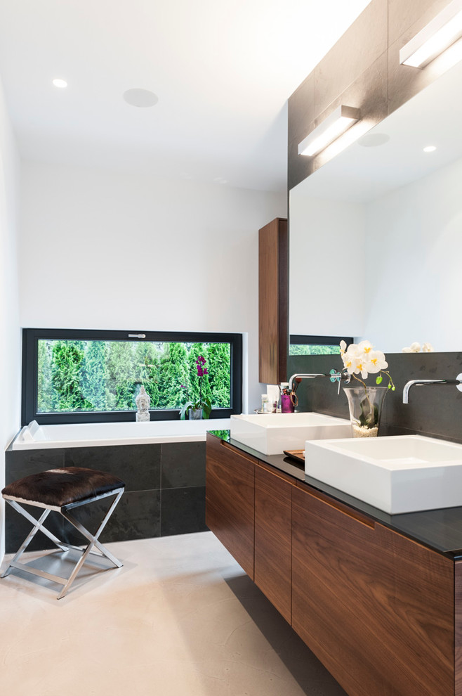 Photo of a large modern bathroom in Munich with flat-panel cabinets, dark wood cabinets, a drop-in tub, a curbless shower, a wall-mount toilet, black tile, slate, white walls, concrete floors, a vessel sink, wood benchtops, grey floor and an open shower.