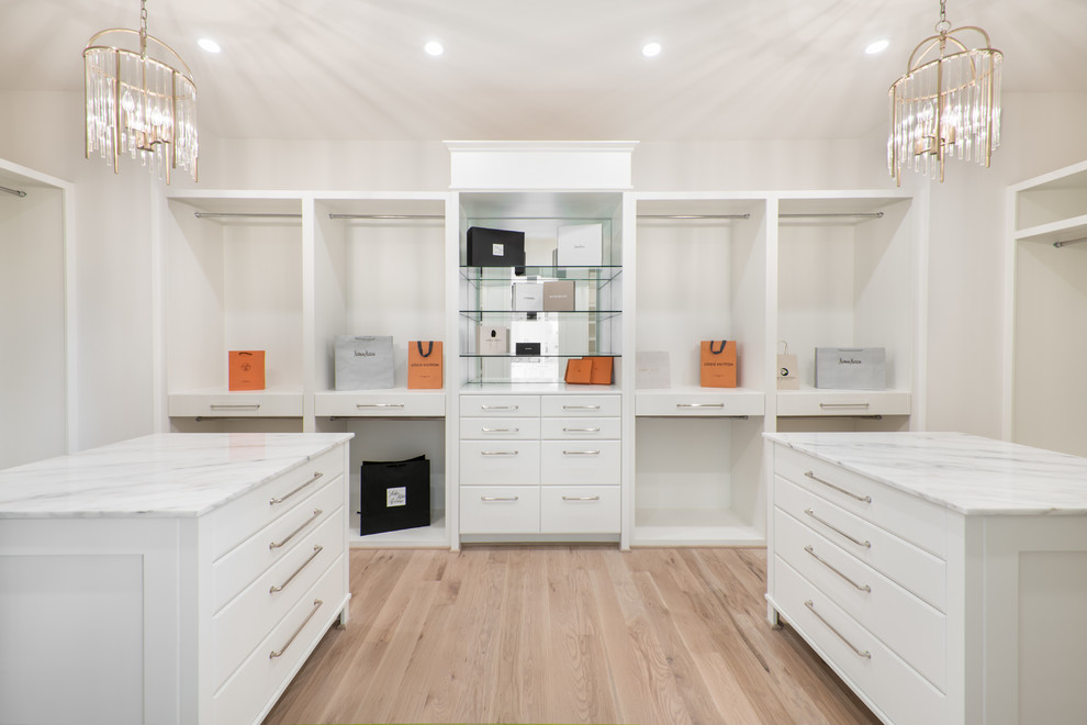 Photo of an expansive contemporary gender-neutral walk-in wardrobe in Houston with flat-panel cabinets, white cabinets, light hardwood floors and beige floor.