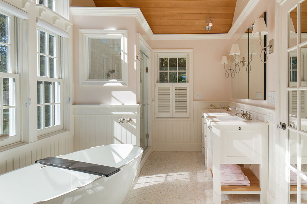 Inspiration for a mid-sized master bathroom in New York with an integrated sink, louvered cabinets, white cabinets, marble benchtops, a freestanding tub, an alcove shower, white tile, pebble tile, white walls and pebble tile floors.