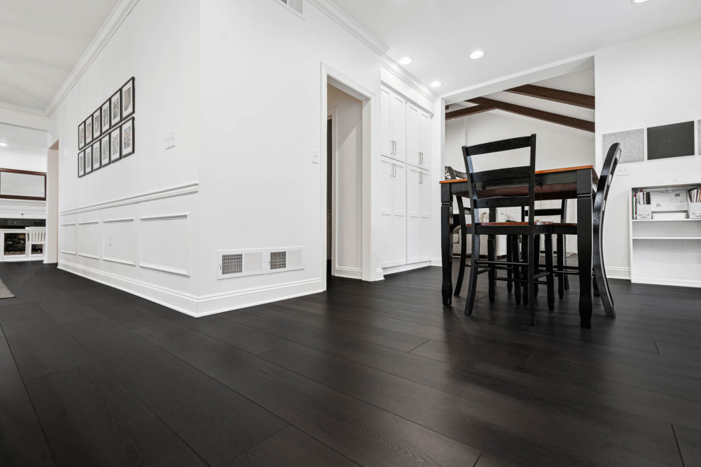 Immagine di una sala da pranzo aperta verso il soggiorno minimalista di medie dimensioni con pareti bianche, pavimento in vinile, pavimento marrone e boiserie