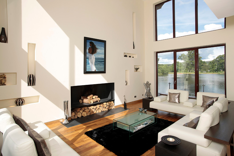 This is an example of a contemporary formal open concept living room in Glasgow with white walls, light hardwood floors and a standard fireplace.
