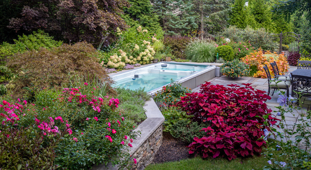 Imagen de piscina clásica pequeña rectangular en patio trasero con paisajismo de piscina y adoquines de piedra natural