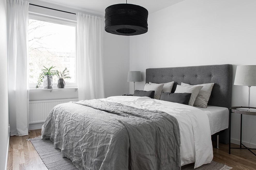 Design ideas for a mid-sized scandinavian master bedroom in Gothenburg with white walls, medium hardwood floors and no fireplace.