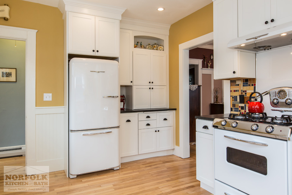 Inspiration for a mid-sized arts and crafts eat-in kitchen in Boston with a single-bowl sink, white cabinets, granite benchtops, multi-coloured splashback, white appliances, light hardwood floors and no island.