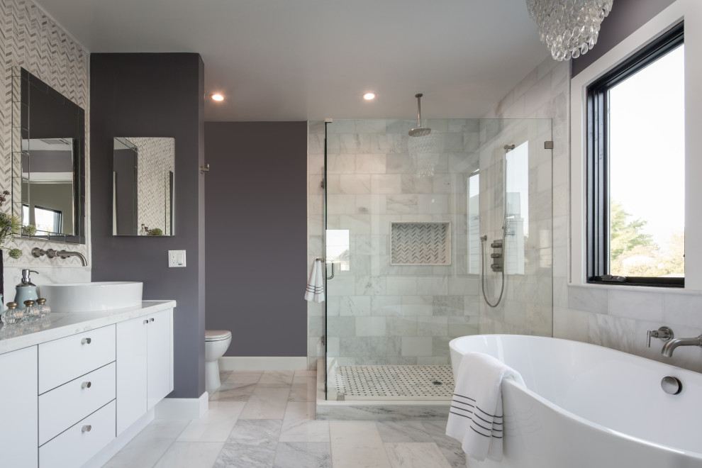 Photo of a mid-sized contemporary master bathroom in Los Angeles with flat-panel cabinets, white cabinets, a freestanding tub, a corner shower, a one-piece toilet, white tile, porcelain tile, grey walls, porcelain floors, marble benchtops, grey floor, a hinged shower door, white benchtops, a niche, a double vanity and a built-in vanity.