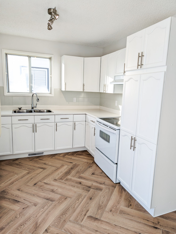 Kitchen - small u-shaped laminate floor kitchen idea in Edmonton with a drop-in sink, recessed-panel cabinets, white cabinets, laminate countertops, gray backsplash, ceramic backsplash, white appliances and beige countertops