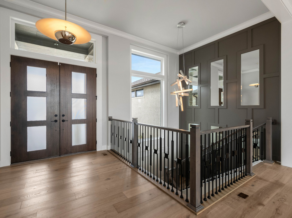Photo of a transitional foyer in Kansas City with grey walls, medium hardwood floors, a double front door, a dark wood front door, brown floor and panelled walls.